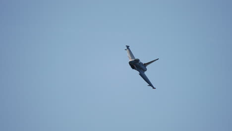 Military jet approaching camera while banking left with visible canopy filmed in slow motion