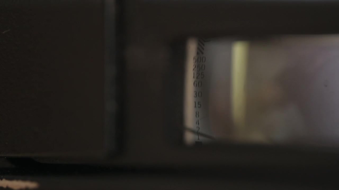 Abstract macro through a vintage camera's viewfinder – unclear at first, then the tiny shutter speed numbers come into focus as sharp typography. An intimate look inside analog photography gear.