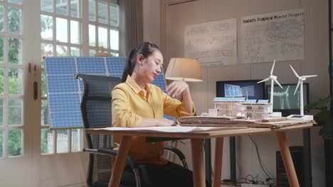 side view of unsatisfied asian woman holding and looking at model of a small house with solar panel