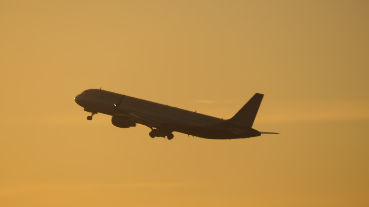 Premium stock video - Plane flying in evening sky against sun flare