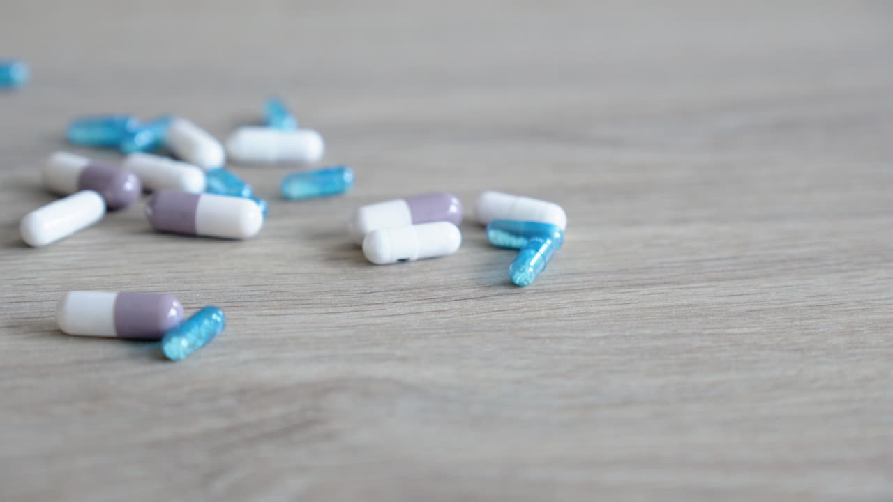 overdose quantities of drug capsules being dropped on a table from a hand