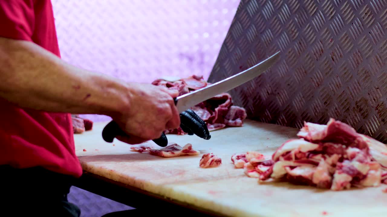 A butcher expertly slices meat on a cutting board in a well-lit kitchen, showcasing precision and craftsmanship