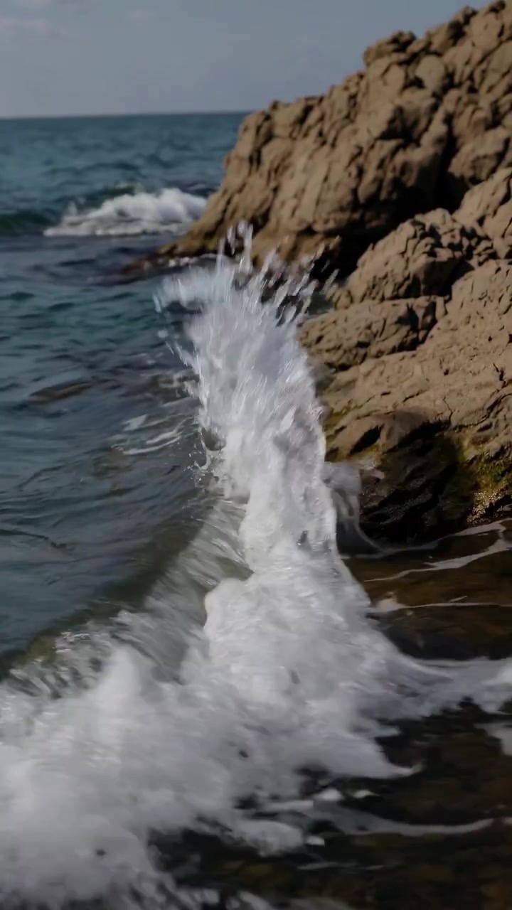Onde dell'oceano che si infrangono contro la costa rocciosa in una giornata di sole