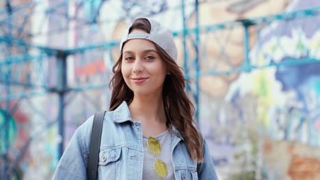 caucasian woman in hipster style wearing cap and looking at the camera in the street