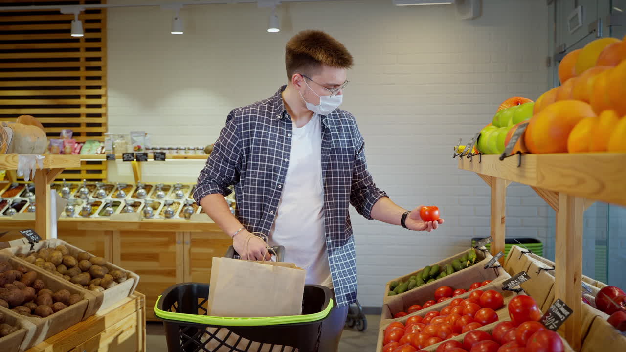 얼굴 마스크를 착용 한 슈퍼마켓에서 식료품을 쇼핑하는 남자