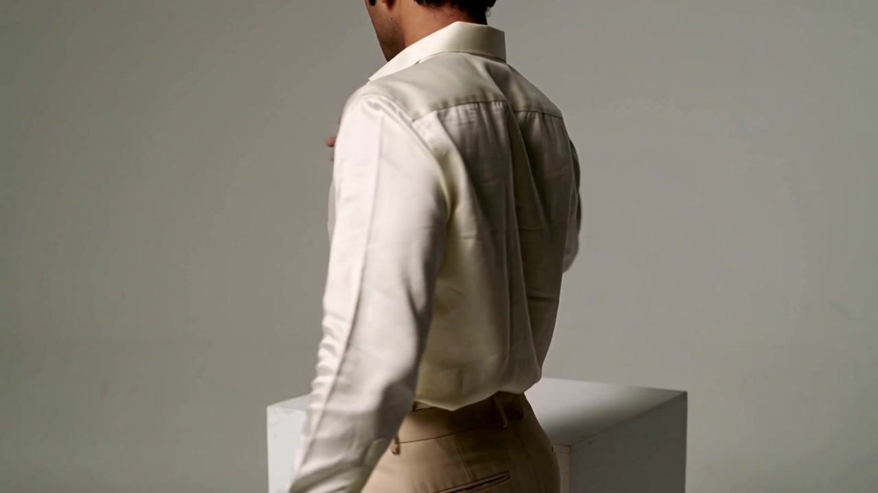 Rotating man modeling on camera cue in studio showing cream shirt beige pants belt loops pedestal