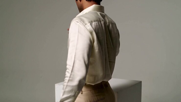 Rotating man modeling on camera cue in studio showing cream shirt beige pants belt loops pedestal