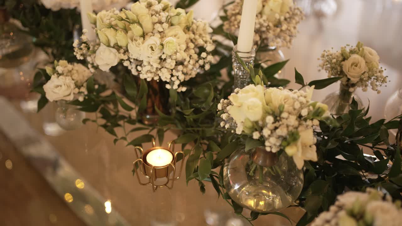 Eleganti composizioni floreali con candele e verde, che creano un'atmosfera morbida e romantica