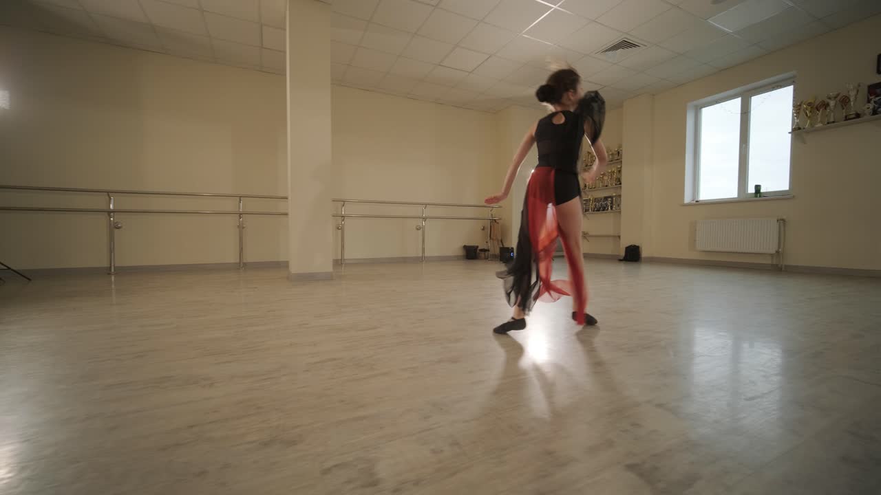 un grupo de jóvenes estudiantes de ballet con ropa de baile negra practicando posiciones en un amplio estudio de ballet con pisos de madera y barras montadas en la pared. expresiones enfocadas y movimientos sincronizados.