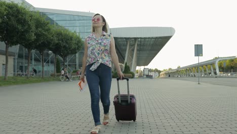 woman tourist walking with luggage from airport. girl stops and start smiling, rejoices. vacation