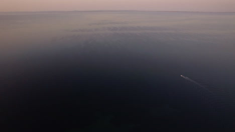 vast sea with sailing motor boat in the distance