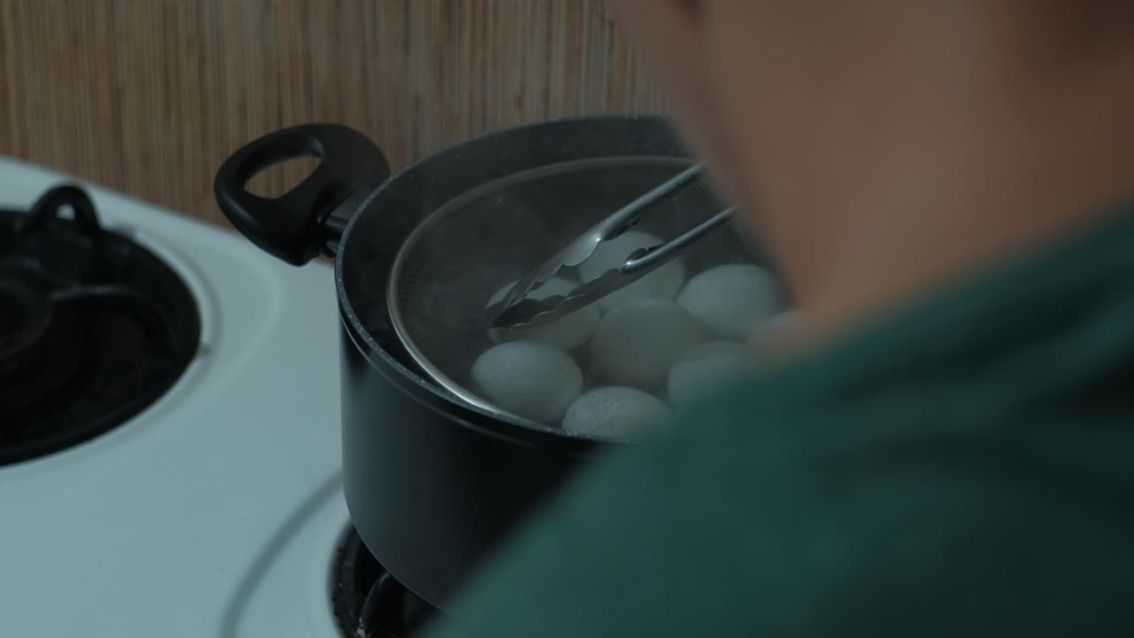 Boiling Fresh Eggs In Pot Over Stove In Kitchen. closeup shot