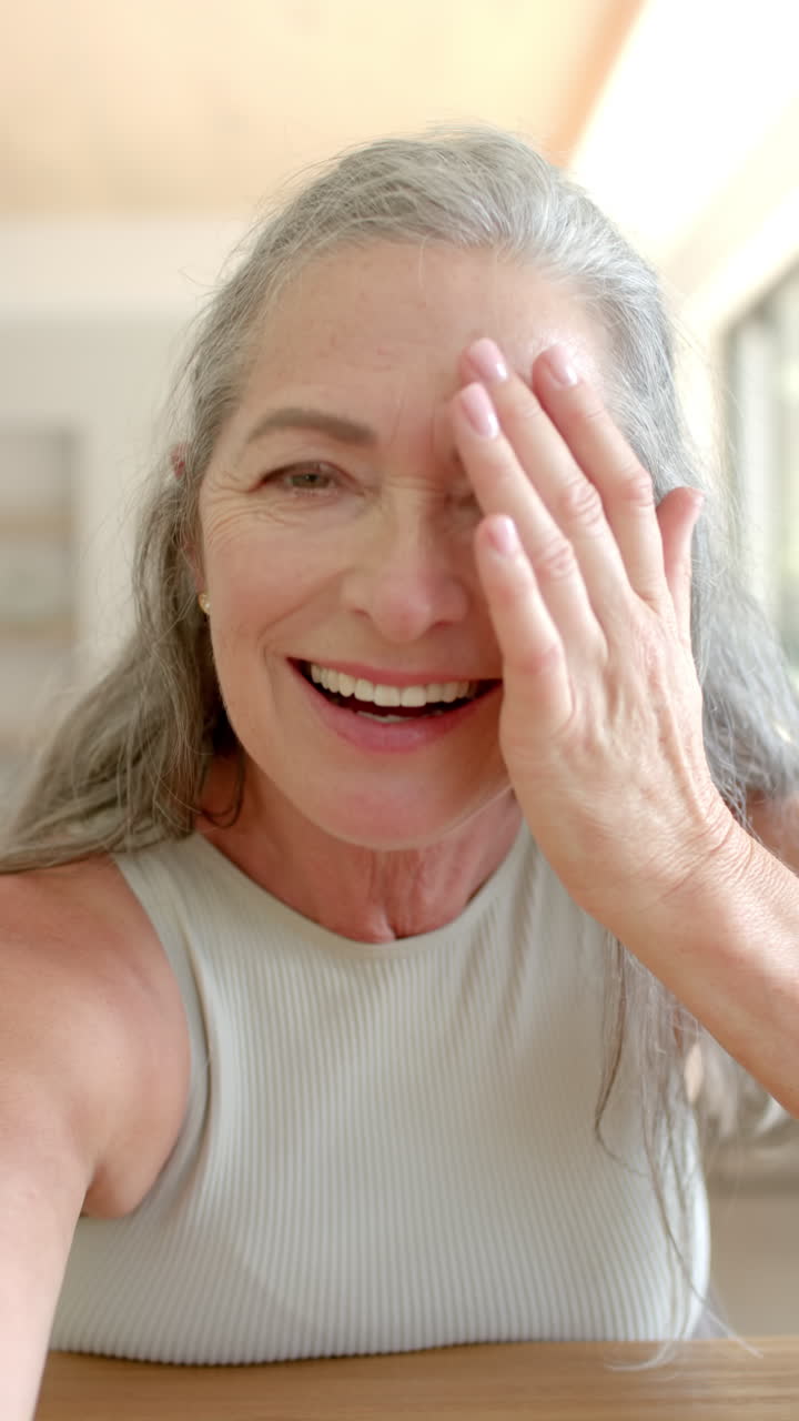 Vertical video: Smiling woman waving hand, enjoying time at home, looking happy and relaxed