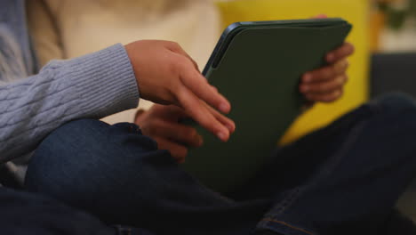 two young boys sitting on sofa at home playing games or streaming onto digital tablet 4