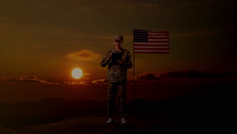 full body of asian man soldier using a tablet while standing with flag of the united states, sunset time