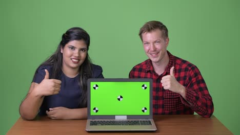 joven pareja de negocios multiétnica juntos contra un fondo verde
