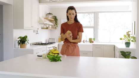 woman preparing fresh salad in bright kitchen, surrounded by fruits and vegetables