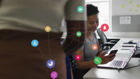 animation of network of digital icons over biracial woman greeting her colleague at office