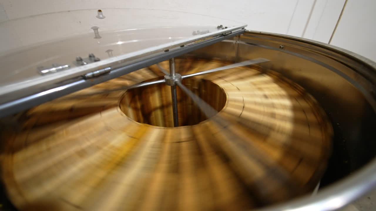 Working machine for honey extracting from wooden frames with honeycombs. Metal barrel with centrifuge mechanism spinning quickly the frames. Top view close up.