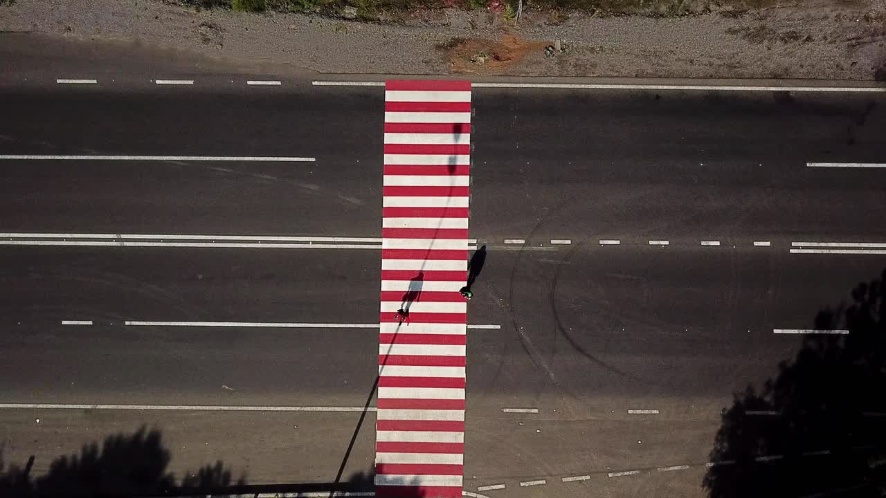 people are crossing the road on a pedestrian of red and white color on the background of the car. Aerial view