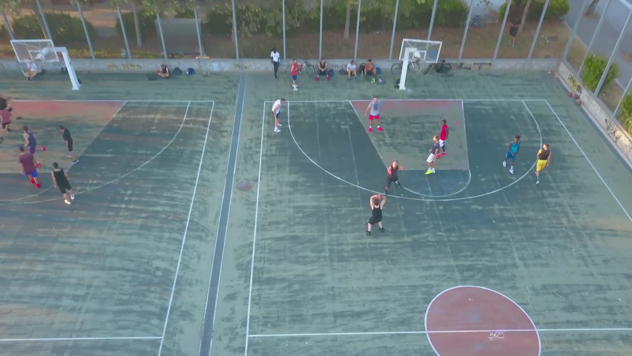 Groups Of Men Playing Basketball At The Basketball Court In Thessaloniki, Greece - aerial drone (tilt-up pullback shot)