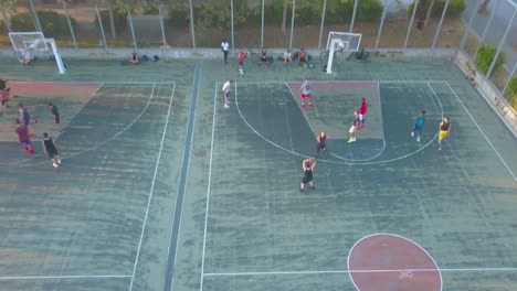 groups of men playing basketball at the basketball court in thessaloniki, greece - aerial drone (tilt-up pullback shot)