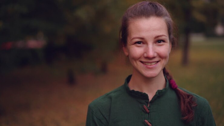 Donna sorridente in maglietta verde in un parco autunnale