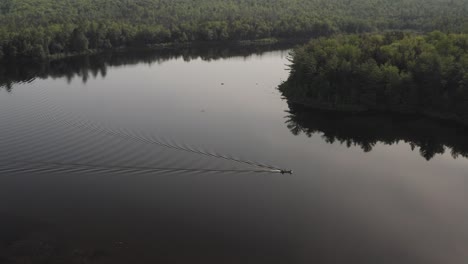 Statische-Luftaufnahme-über-Flachem,-Ruhigem-See-Seeboot-Fährt-über-Die-Von-Wildnis-Umgebene-Oberfläche