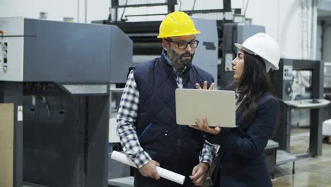 Front-view-of-focused-workers-talking-while-standing-with-laptop