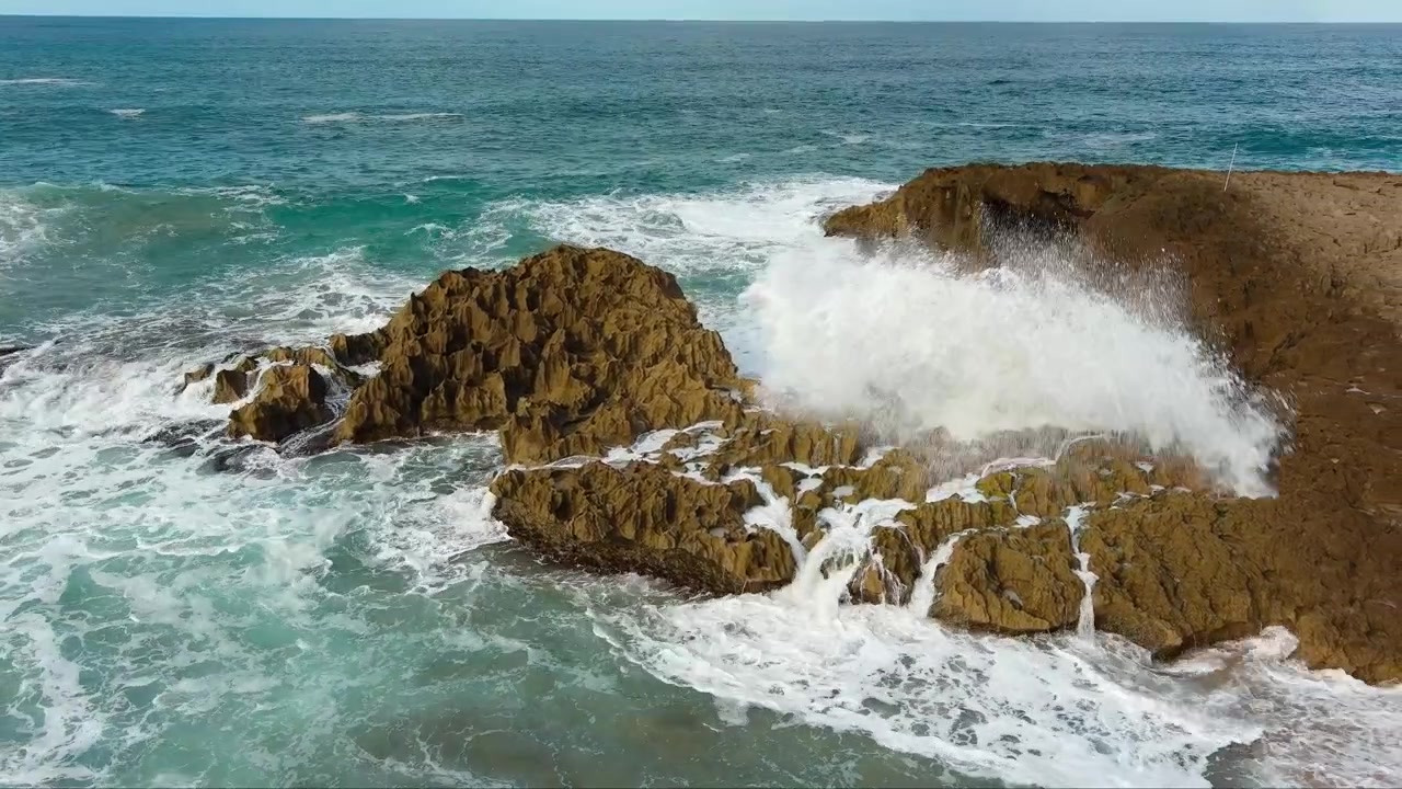 Ripresa aerea 4K con drone in orbita di onde che si infrangono contro le rocce lungo la costa di Porto Rico. Mostra una costa frastagliata e acqua turchese. Per turismo, natura, avventura