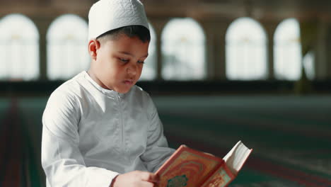 Islam,-child-in-mosque-reading-Quran-for-learning