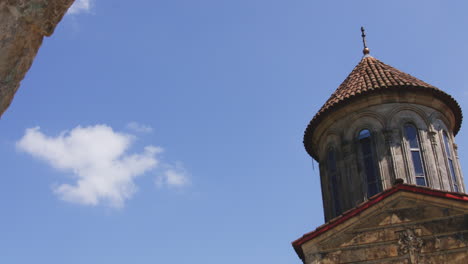 torre de la iglesia de piedra del monasterio de motsameta con techo de tejas bajo un cielo azul