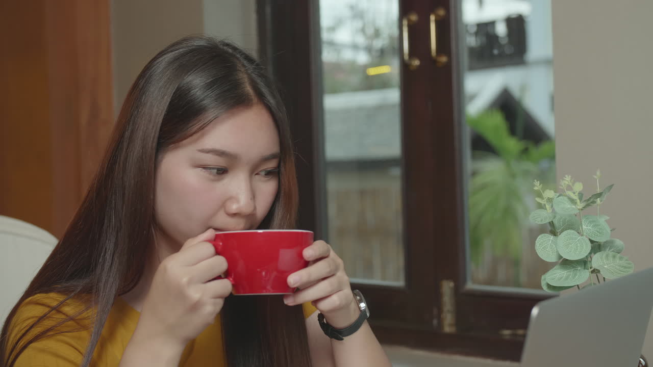 Young Asian Woman Drinking Hot Coffee And Looking Laptop