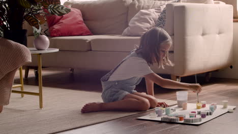 Blonde-Girl-Sitting-On-The-Floor-And-Painting-Animal-Pieces-In-Living-Room-4