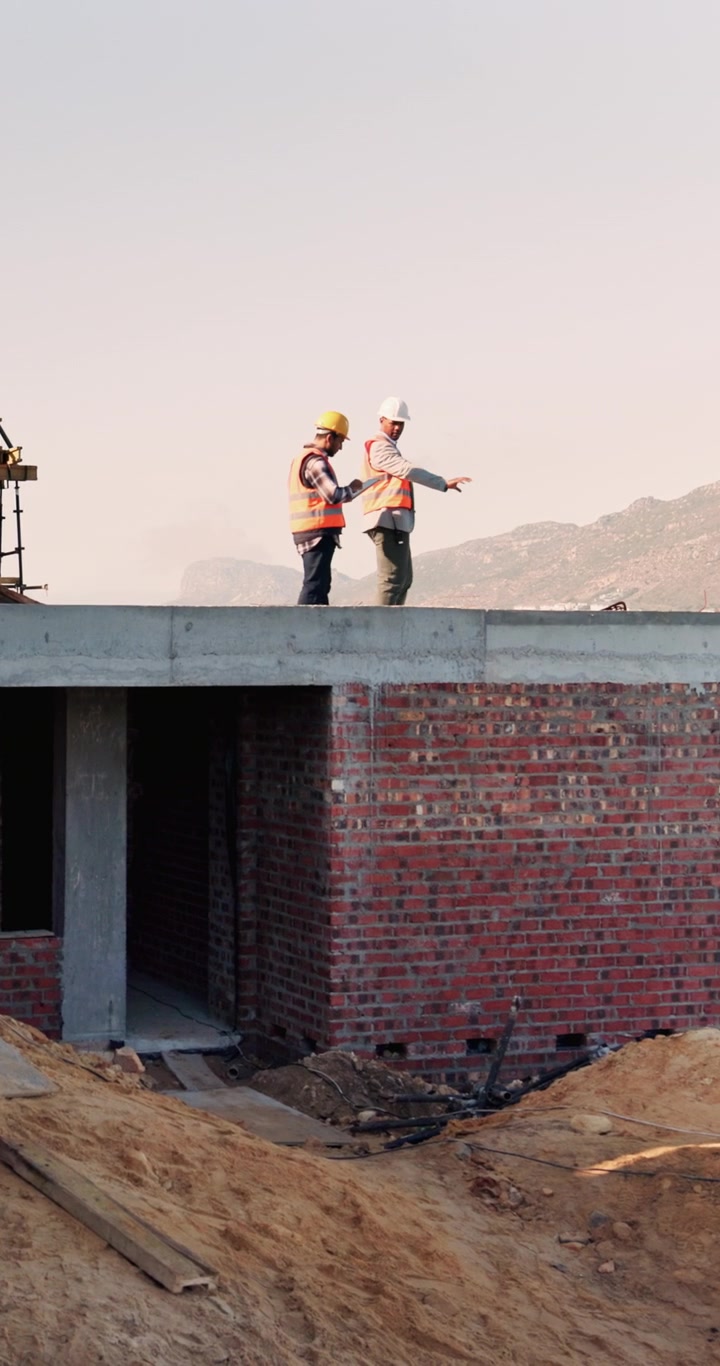 Construction Workers Reviewing Plans on Building Site