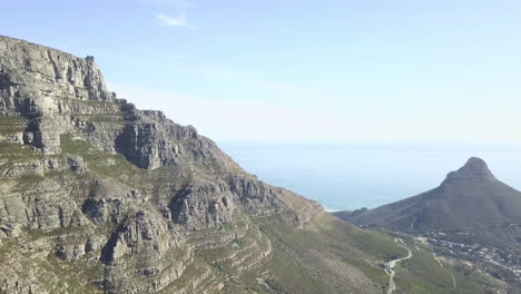 Szenische-Drohnenansicht-Aus-Der-Luft,-Die-über-Den-Tafelberg-Mit-Seinen-Steilen,-Majestätischen-Sandsteinfelsen-Gegen-Einen-Hellblauen-Atlantik-Und-Einen-Himmel-Mit-Cirruswolken-Aufsteigt