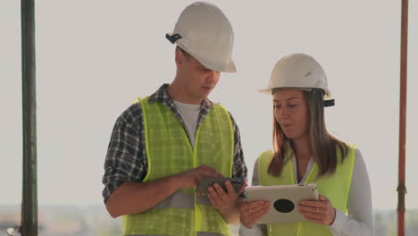 supervisor de un edificio en construcción hombre discutiendo con ingeniero diseñador mujer el progreso de la construcción y examina un plan de construcción.