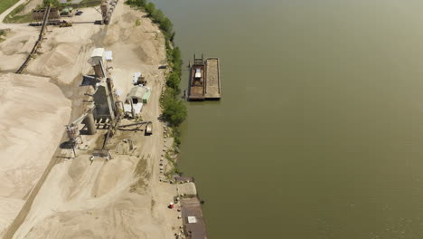 montón de arena y barcazas en la planta de arena y grava junto al río arkansas en van buren, arkansas