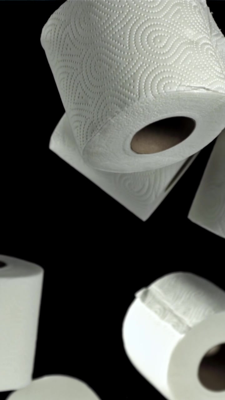 White Toilet Paper Rolls Floating Upwards on Black Background