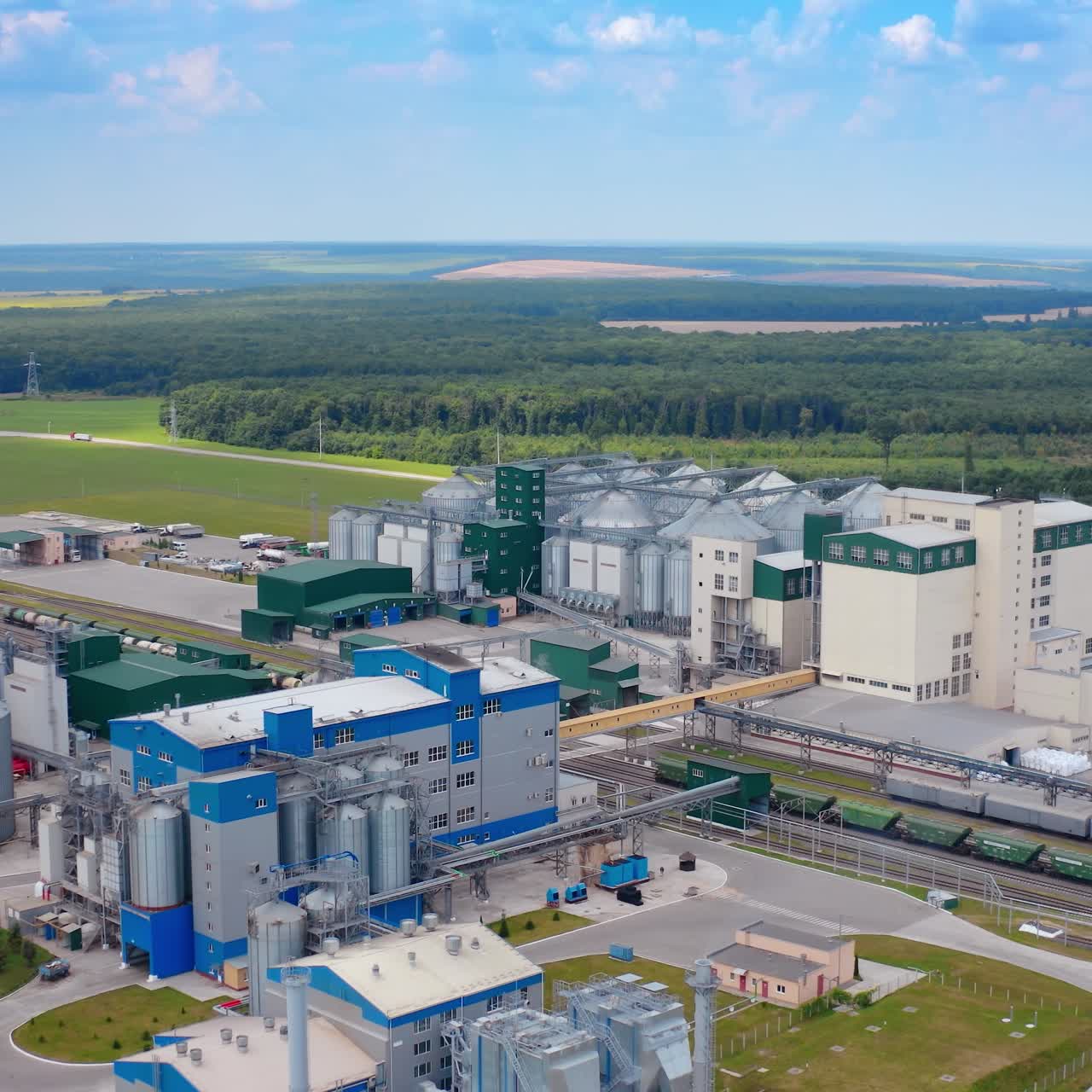 Modern warehouse under blue sky. Steel grain elevators for grain storage. Agriculture industry. Innovative plant for agribusiness