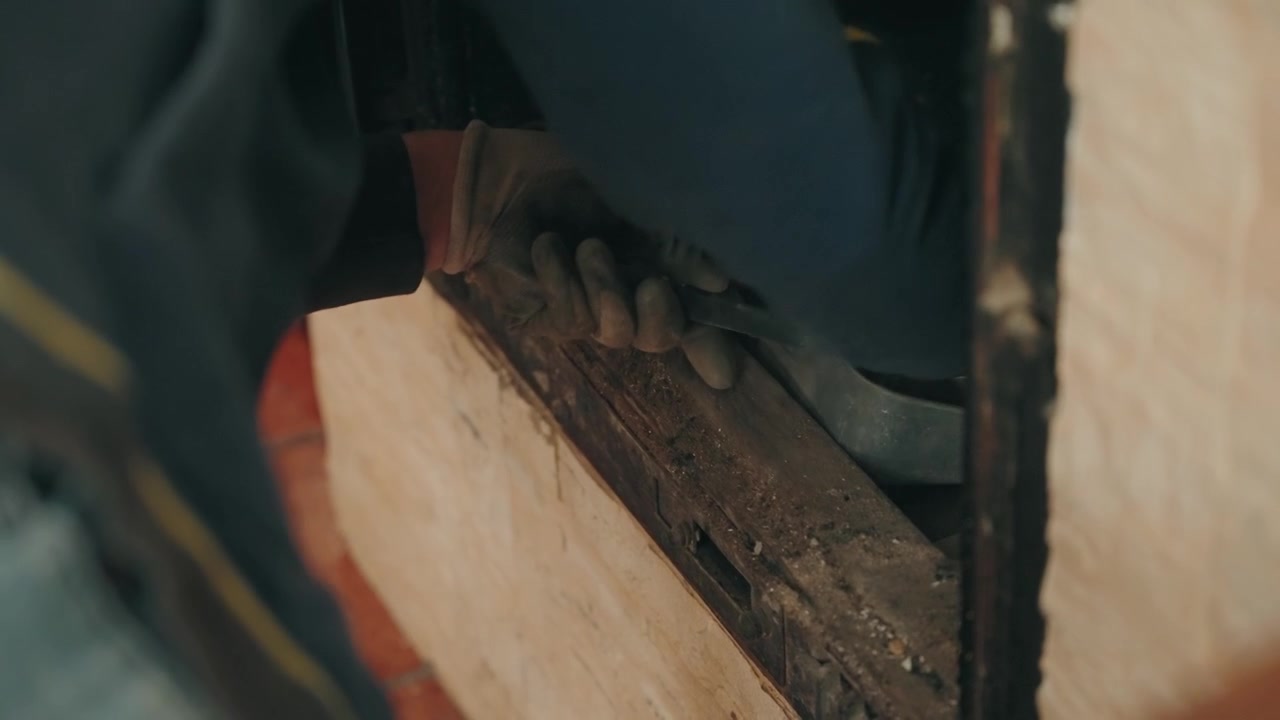 Close up person brushing ash and debris from metal fireplace stove grate