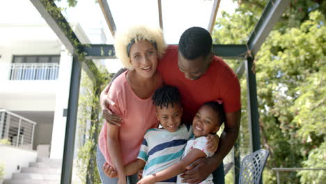 familia de afroamericanos padre abraza a una joven madre biracial y dos niños alegres