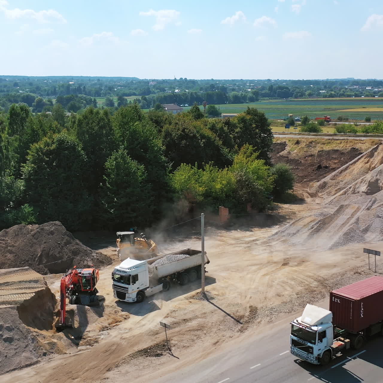 Heavy machinery with stones. New road with moving transport near the piles with stones. Trucks loading granite stones. Aerial shot.