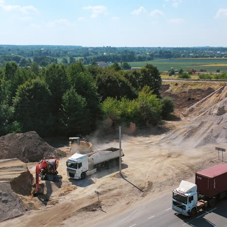 heavy machinery with stones. new road with moving transport near the piles with stones. trucks loading granite stones. aerial shot.