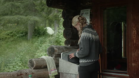 hermosa chica rubia nórdica cocinando fuera de una cabaña en el desierto en el bosque final, en el sendero karhunkierros en el parque nacional de oulanka, finlandia