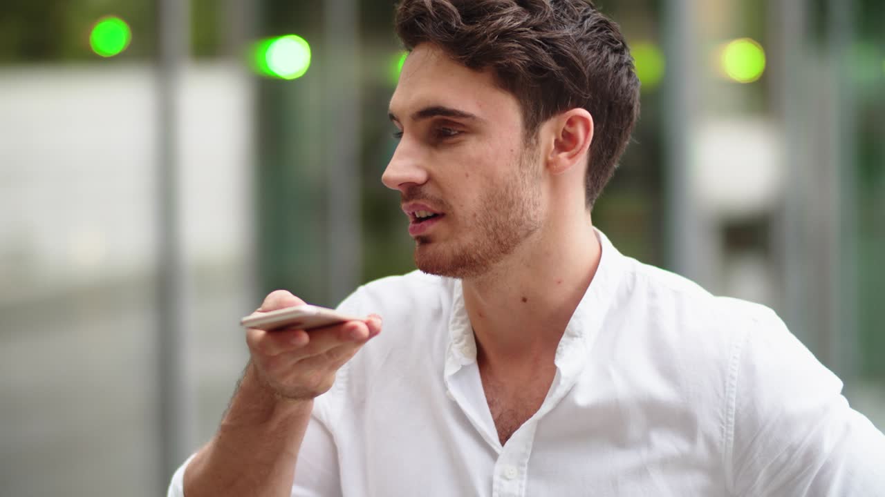 hombre de negocios serio comunicándose por mensaje de voz en el teléfono móvil al aire libre