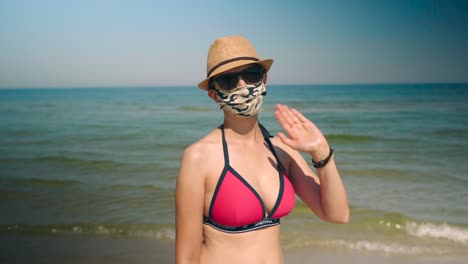 Mujer-Joven-En-Bikini-En-La-Playa-Con-Ondas-De-Máscara-Facial-Corona-En-La-Cámara