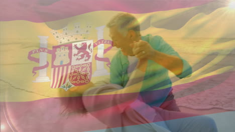 animation of flag of spain over happy senior caucasian couple dancing on beach