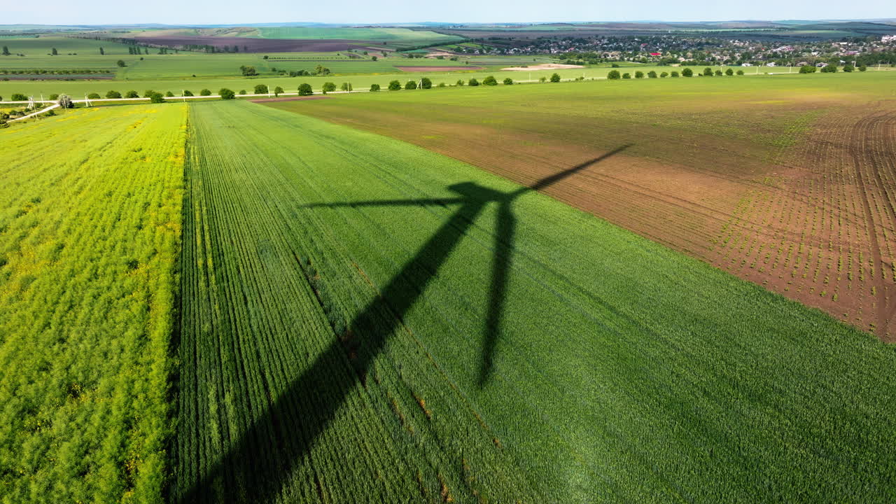 Aerial drone view of a wind turbine shadow on an agricultural field