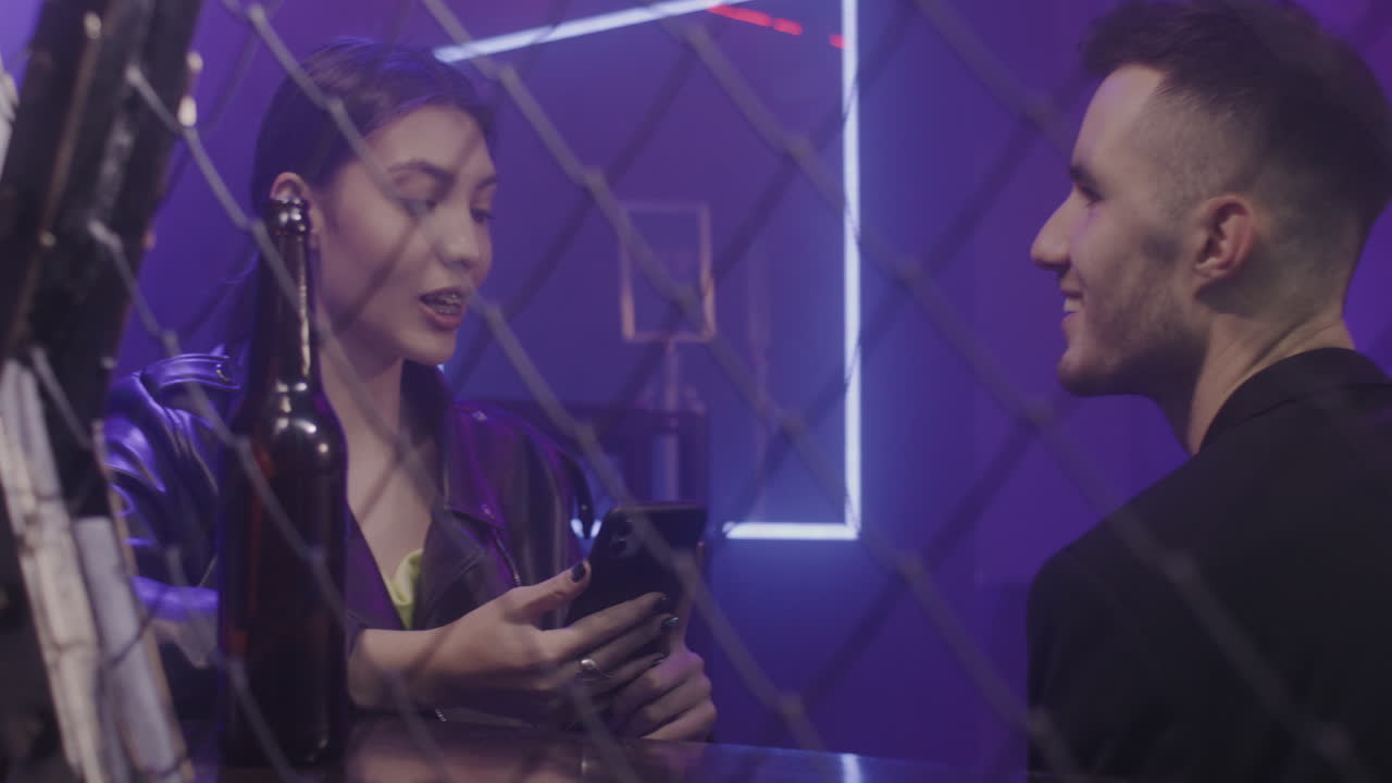 디스코 클럽에 앉아있는 동안 함께 이야기하고 웃는 젊은 친구의 커플